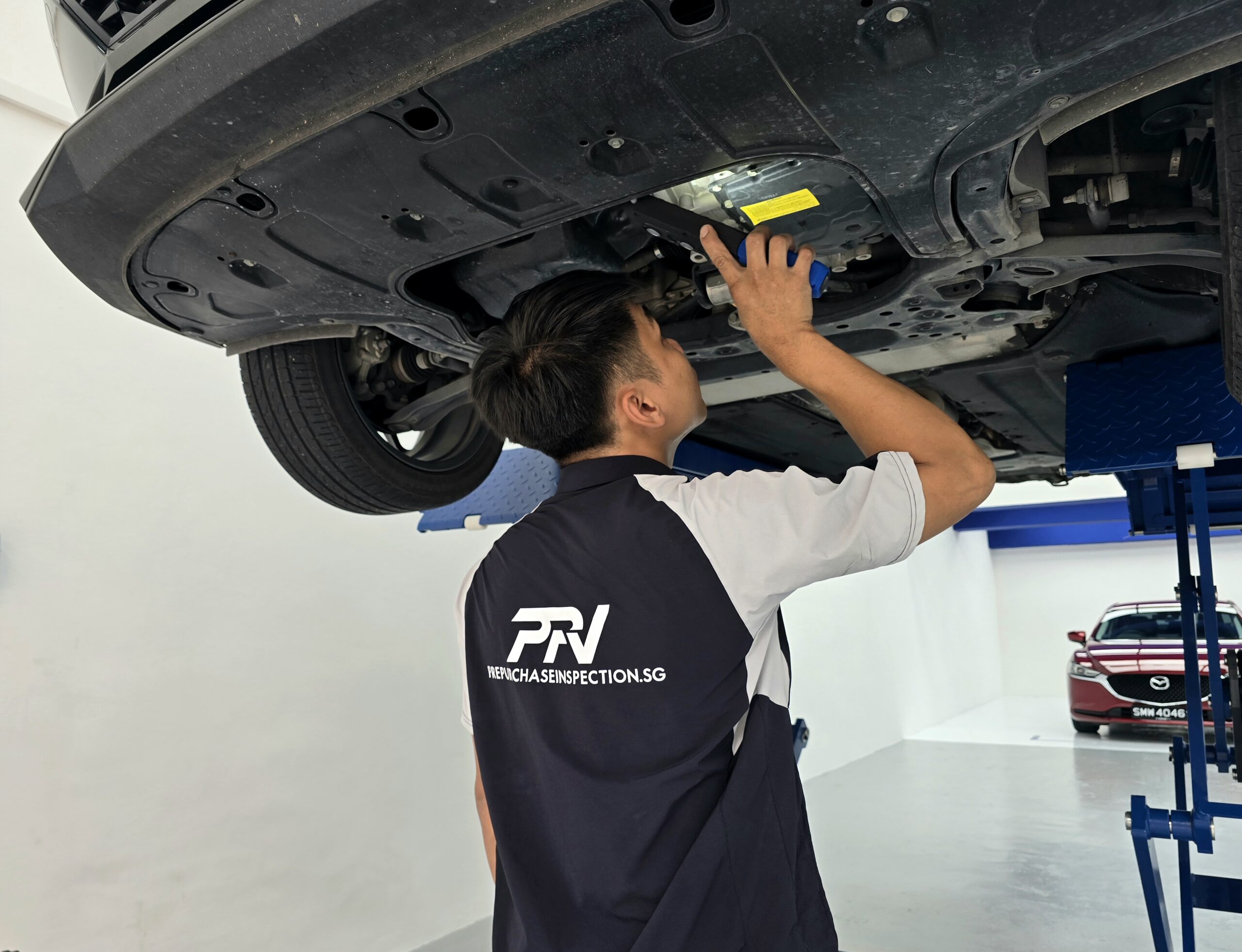 Mechanic performing undercarriage inspection on a used car